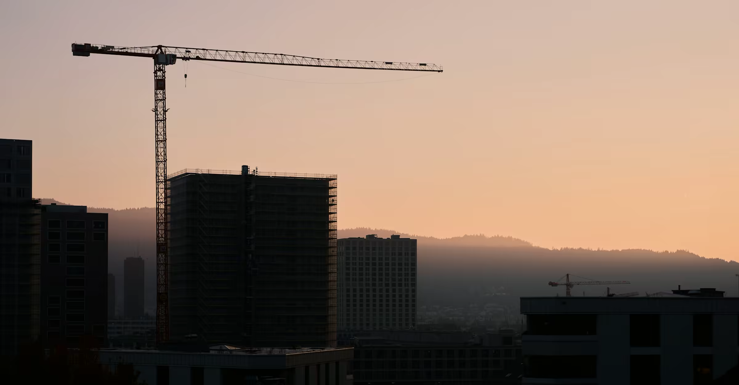 Grúa de construcción al atardecer sobre un edificio en obra